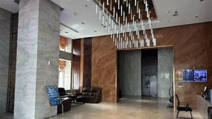 A modern lobby with a marble floor, a reception desk, leather seating, and a hanging light fixture. - Renhe International Hotel (Jarud Banner)