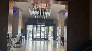 A modern lobby with a glass door entrance, a reception desk, and a chandelier. - Renhe International Hotel (Jarud Banner)