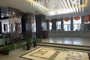 Un hall de hotel con una recepción, un separador decorativo y una alfombra estampada.