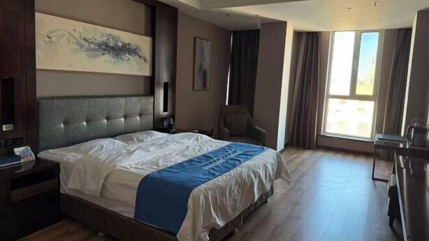 A hotel room with a large bed, a desk, a chair, a TV, and a window. - Renhe International Hotel (Jarud Banner)
