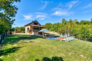 A house with a swimming pool, a covered patio, and a lawn with lounge chairs. - Jungle House With Pool and Hot Tub (Sveti Ivan Zelina)