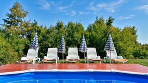 A swimming pool with lounge chairs and striped umbrellas.