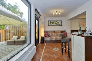 A room with a sofa, a bar area, and a window overlooking a garden. - Twin Oasis Retreat With Pool & Spa (Sveti Ivan Zelina)