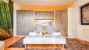 A modern bedroom with a bed, a wardrobe, and a large window.