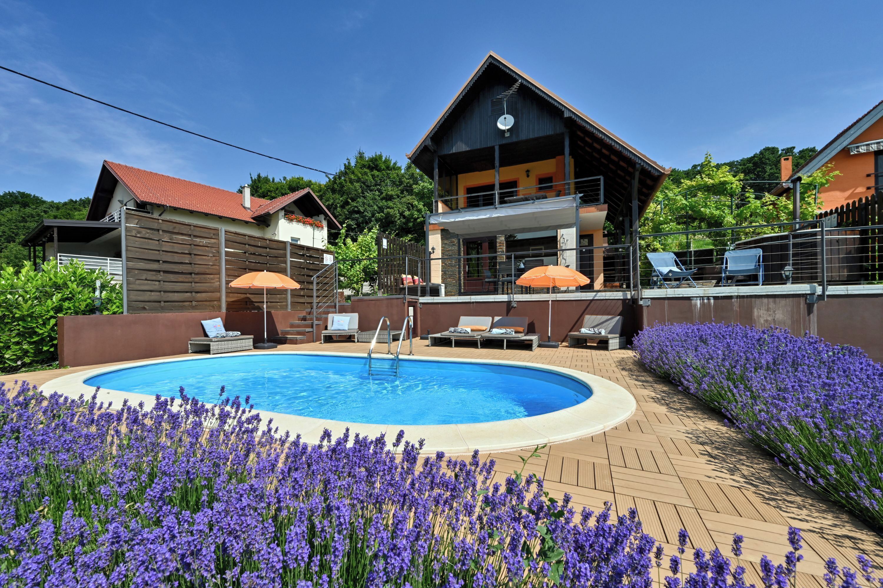 A pool area with a wooden deck, lounge chairs, and a building with a balcony.