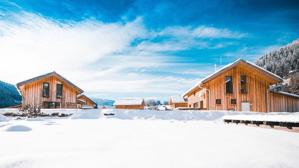 A wooden cabin complex with a snowy landscape and mountains in the background. - Chalet # 22 with 4 bedrooms & sauna (Murau)