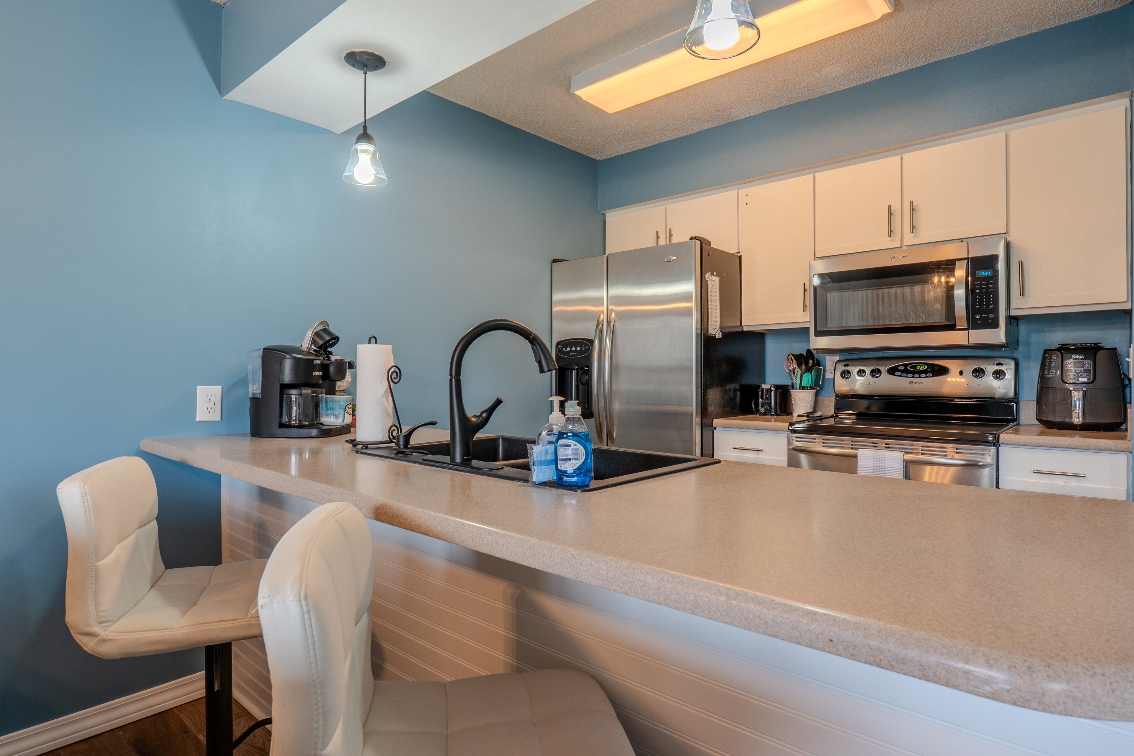 A modern kitchen with a central island, stainless steel appliances, and white cabinetry.