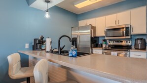 Una cocina moderna con una isla central, electrodomésticos de acero inoxidable y armarios blancos.
