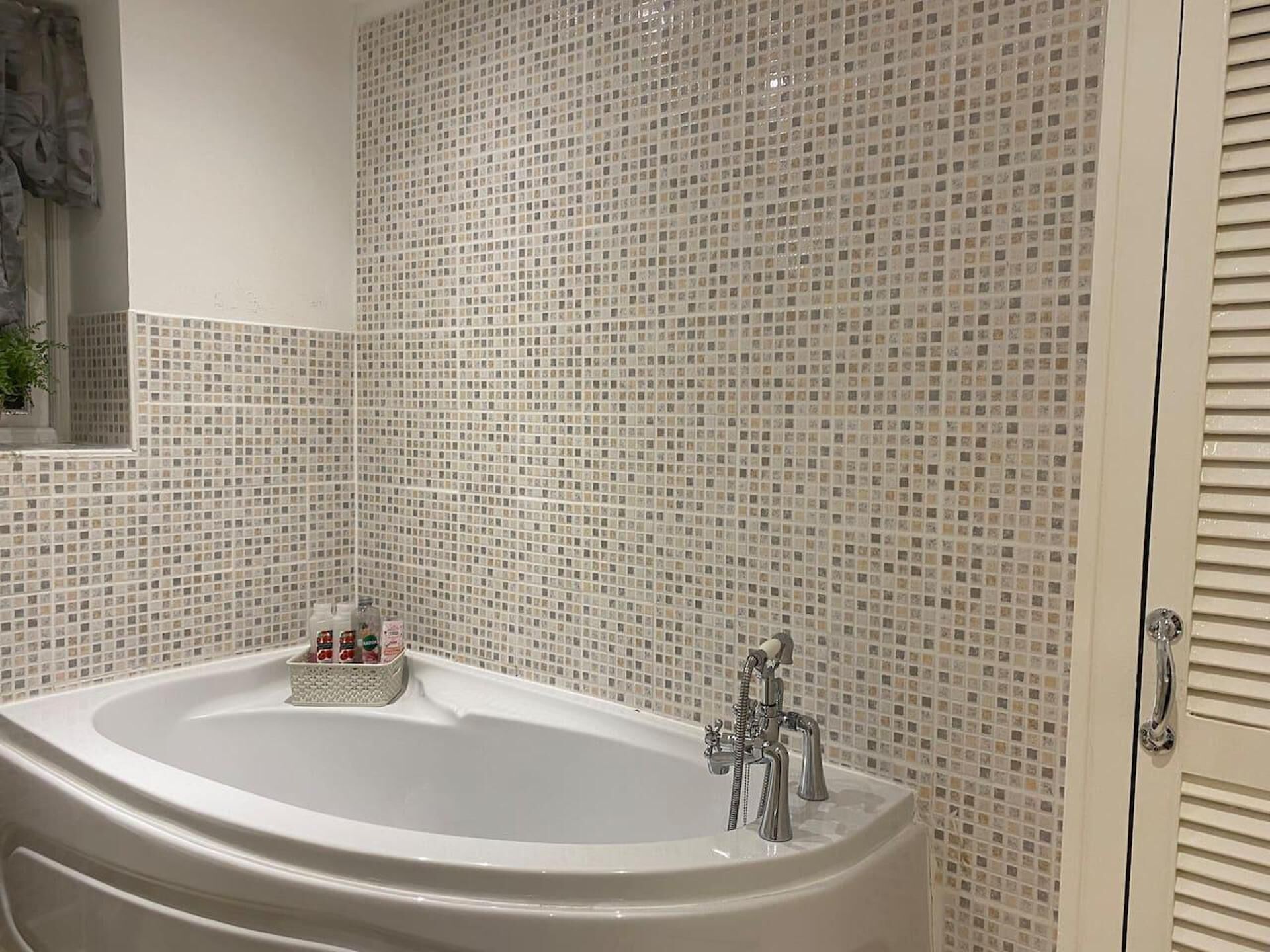 Um banheiro com uma banheira grande, paredes revestidas de azulejos e uma janela com vista.