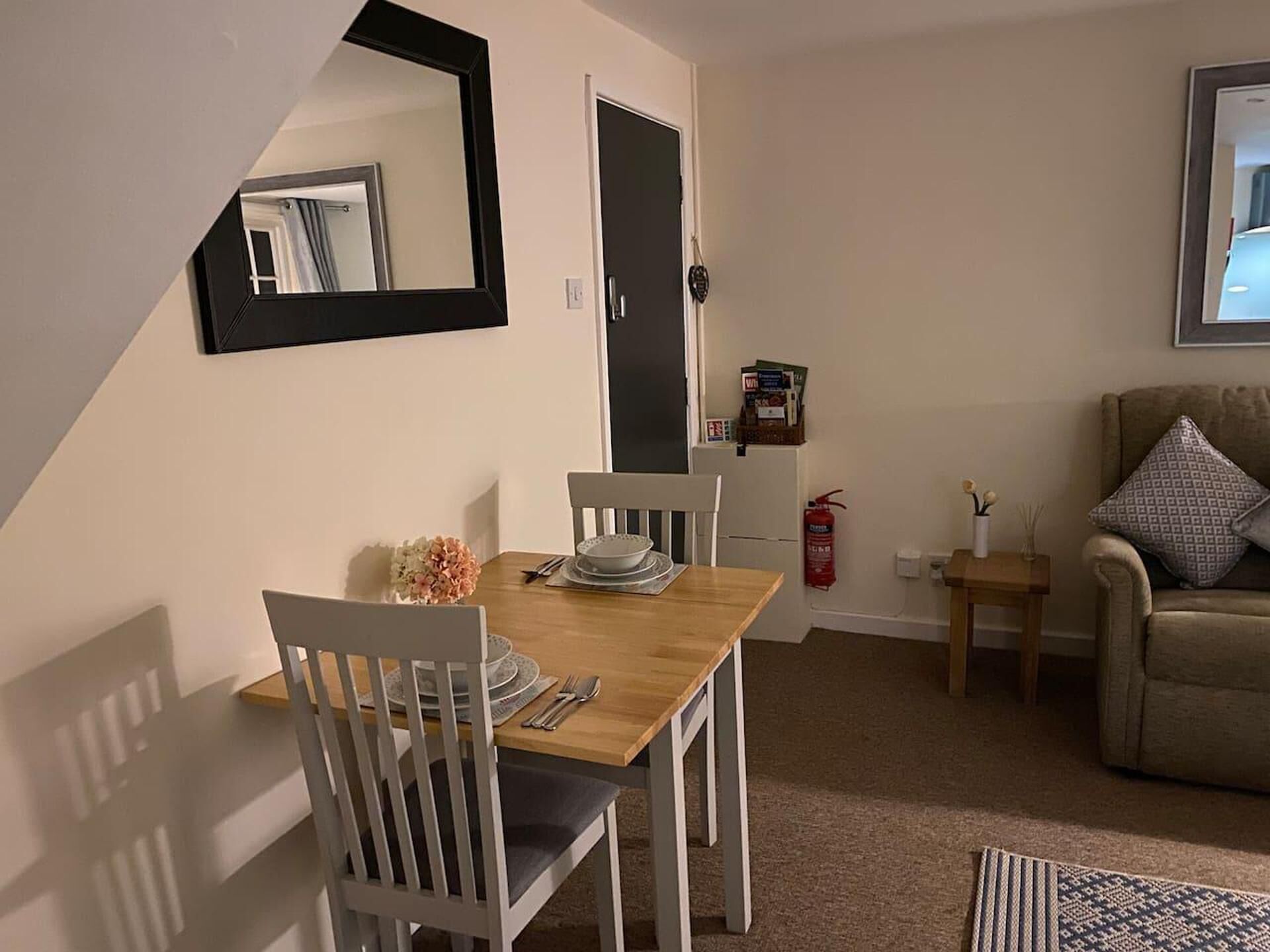 A dining area with a wooden table, white chairs, and a mirror on the wall.