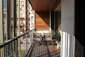 A balcony with a wooden floor, a metal railing, and a bench with cushions. - SUN ON PASSEIG DE GRACIA (Barcelona)