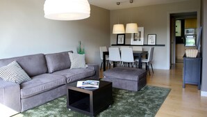 Un salon moderne avec un canapé gris, une table basse et un coin repas comprenant des chaises et une table.