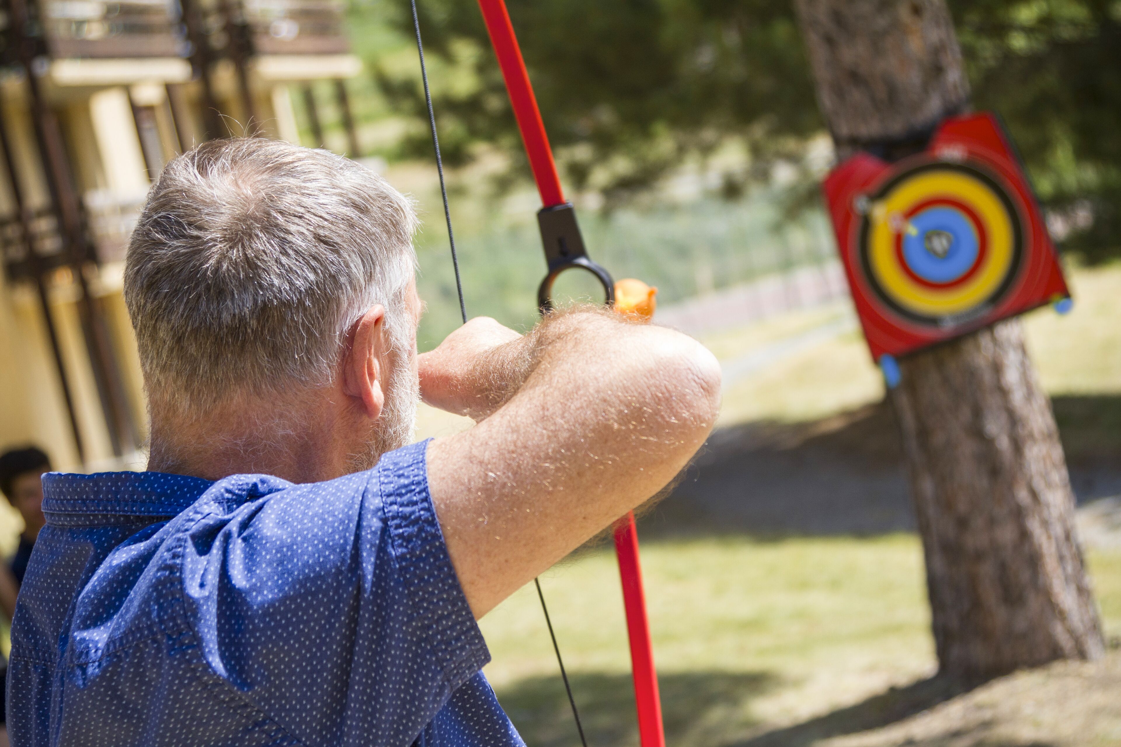 A person aiming a bow at an archery target.