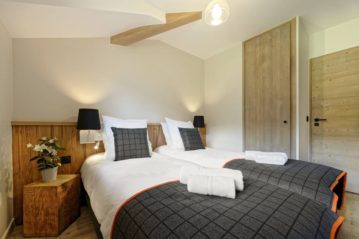 Un lit double avec une couverture à carreaux, une table de chevet avec une lampe et une tête de lit en bois.