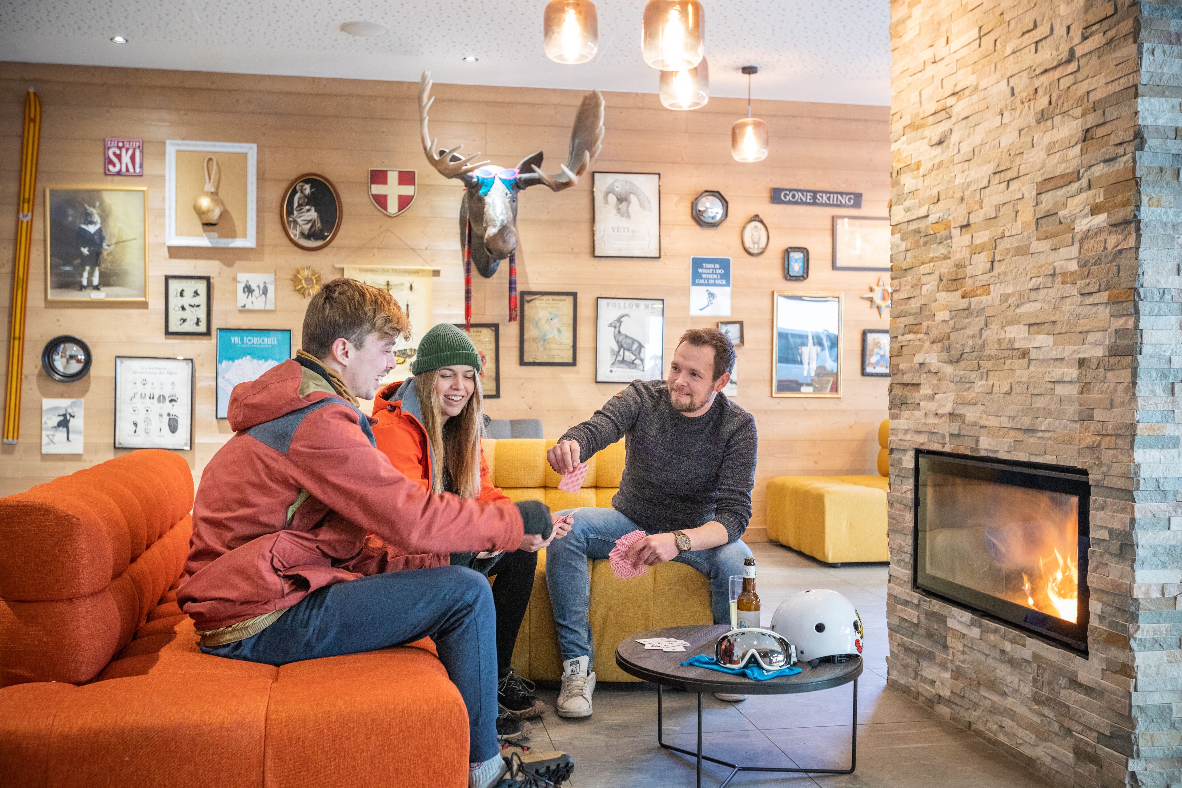 A cozy indoor setting with a fireplace, wooden walls, and various framed pictures and trophies.