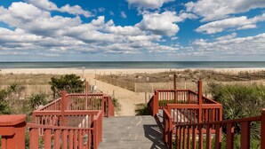 A wooden staircase leading to a beach with a clear sky and clouds.