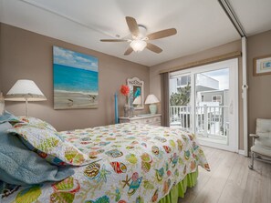 Un dormitorio con cama, ventilador de techo y vista al exterior.