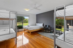 Ein modernes Hotelzimmer mit Etagenbett, einem Einzelbett, Deckenventilator und Blick ins Freie.