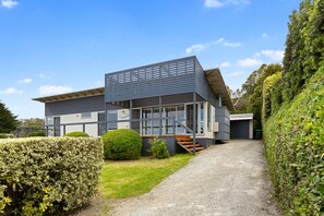 A modern building with a sloped roof, a staircase leading to the entrance, and a gravel driveway. - Great Ocean Road Lodge (Skenes Creek)