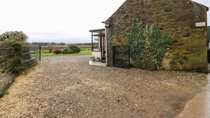 Un bâtiment en pierre avec une allée gravillonnée et un portail en métal.
