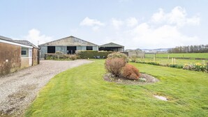 Une propriété rurale avec une allée de gravier menant à une grande grange et à un bâtiment plus petit.