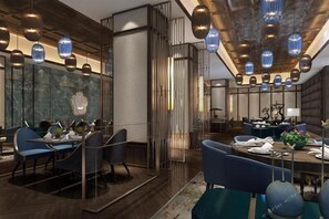 A modern dining area with a high ceiling, pendant lighting, and a central table with chairs. - Jinling Hotel (Chongqing)
