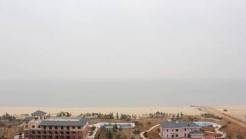 A resort with multiple buildings, a pool area, and a beach view.
