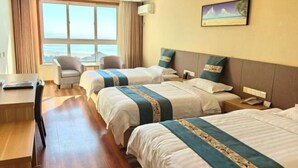Quarto de hotel com duas camas, uma escrivaninha, uma cadeira, uma mesinha de cabeceira e um quadro na parede.