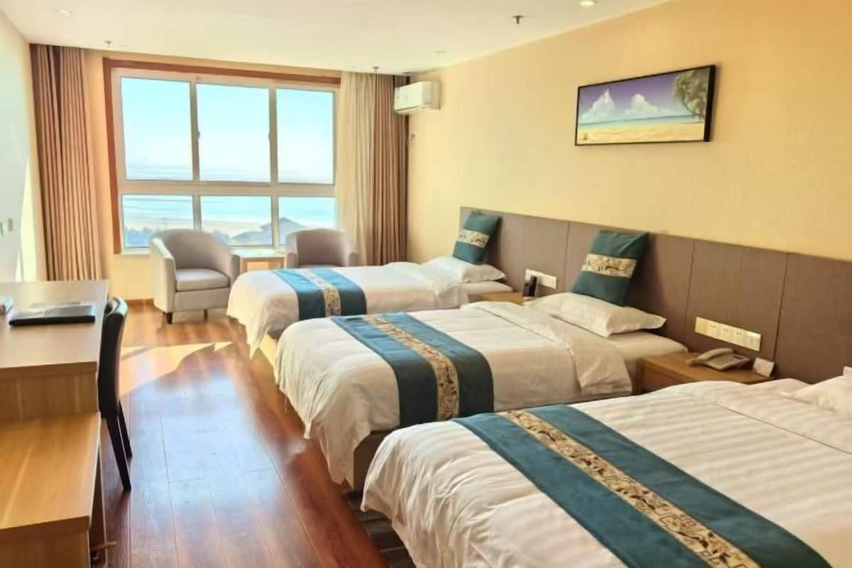Ein Hotelzimmer mit zwei Betten, einem Schreibtisch, einem Stuhl, einem Nachttisch und einem Bild an der Wand.