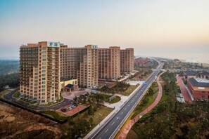 Un ensemble immobilier résidentiel de grande hauteur, composé de plusieurs étages, avec une cour intérieure et une route menant à la plage.