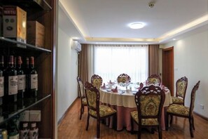 Un coin repas avec une table ronde, des chaises et un meuble à bouteilles.