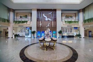 Un hall d’entrée spacieux, agrémenté d’une table décorative centrale, d’un grand mur avec des stores verticaux et d’un comptoir de réception.