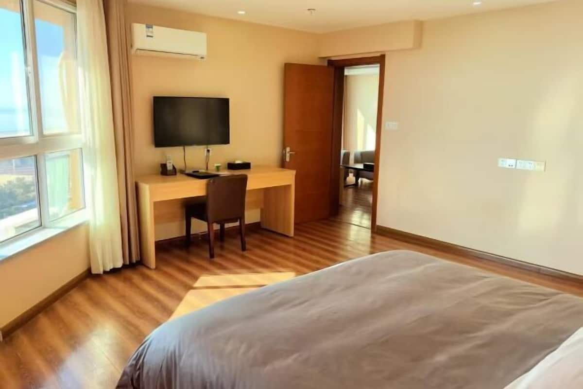 Ein Hotelzimmer mit einem Bett, einem Schreibtisch, einem Stuhl, einem Fernseher und einem Fenster.
