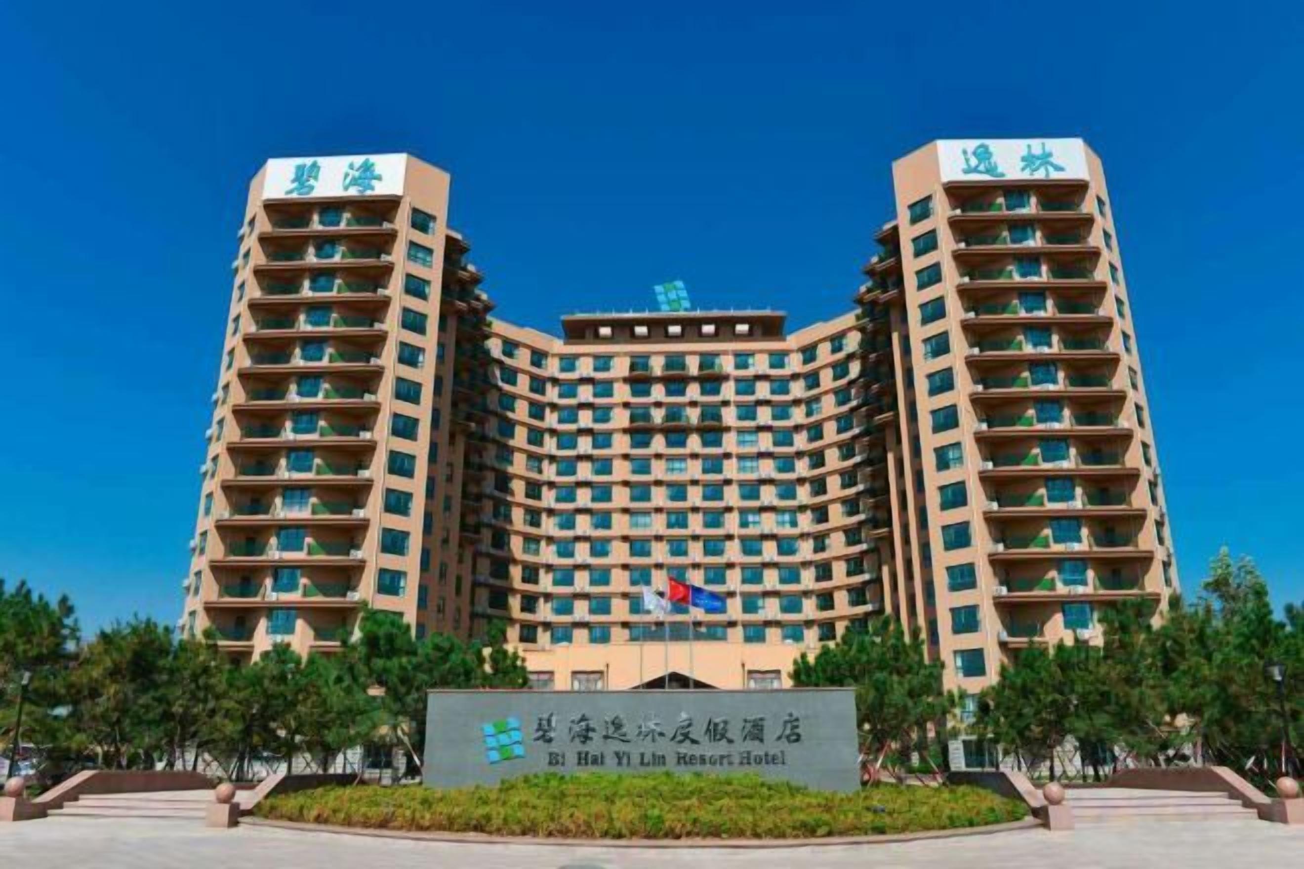 Un edificio de hotel de varios pisos con fachada curva, múltiples balcones y un cartel frontal que indica el nombre del hotel.