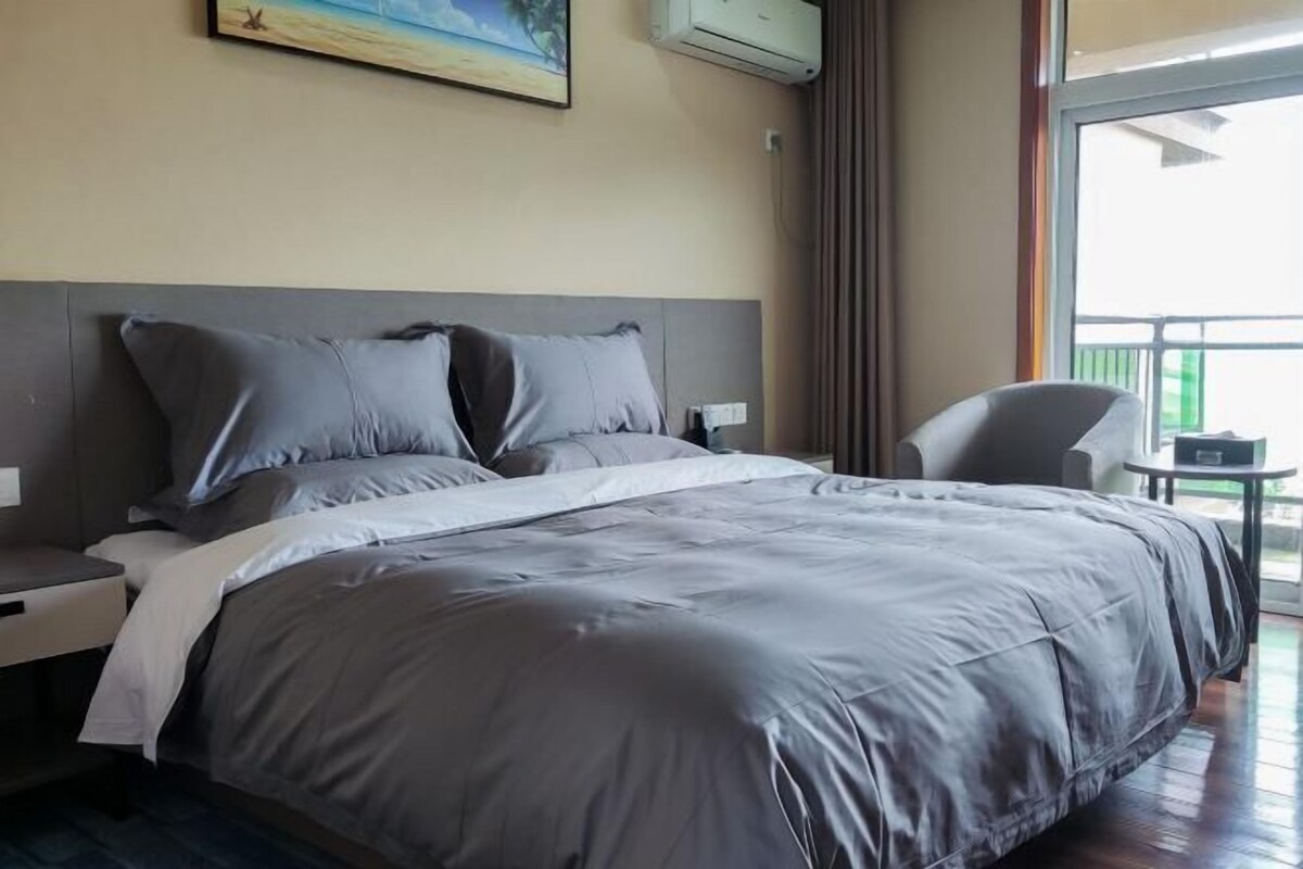 Une chambre d’hôtel avec un grand lit, une table de chevet, une chaise et une petite table.