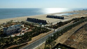 Um hotel à beira-mar com vista para a praia, área de estacionamento e um jardim ajardinado.