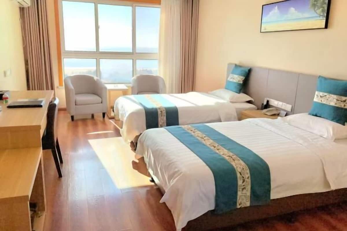 Ein Hotelzimmer mit zwei Betten, einem Schreibtisch und einem Stuhl.