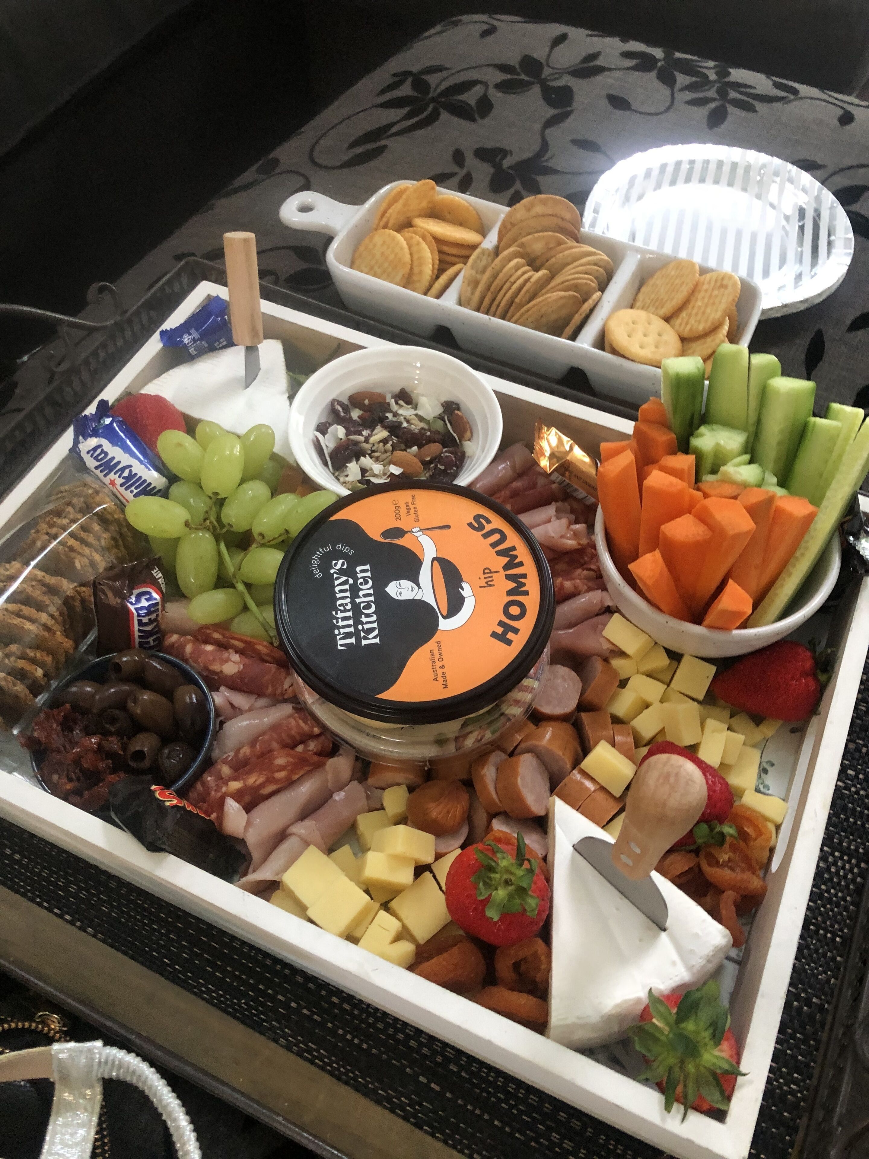 A charcuterie board with various cheeses, meats, fruits, and crackers.