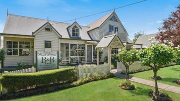 A two-story house with a sign advertising 'Creek Cottage B&B' and '3 Luxurious Suites'.