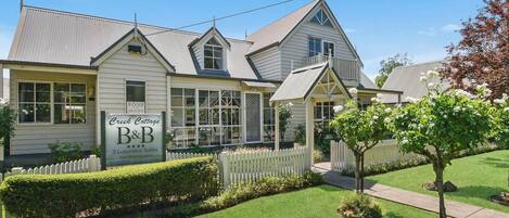 Una casa de dos pisos con un cartel que anuncia 'Creek Cottage B&B' y '3 Suites de Lujo'.