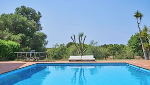 A rectangular swimming pool with clear blue water, surrounded by a wooden deck. There are white lounge chairs and a small table with a canopy. - Fandango  Stunning Finca near Cala Dor with Large Garden and Private Pool, A/C (balearic islands)