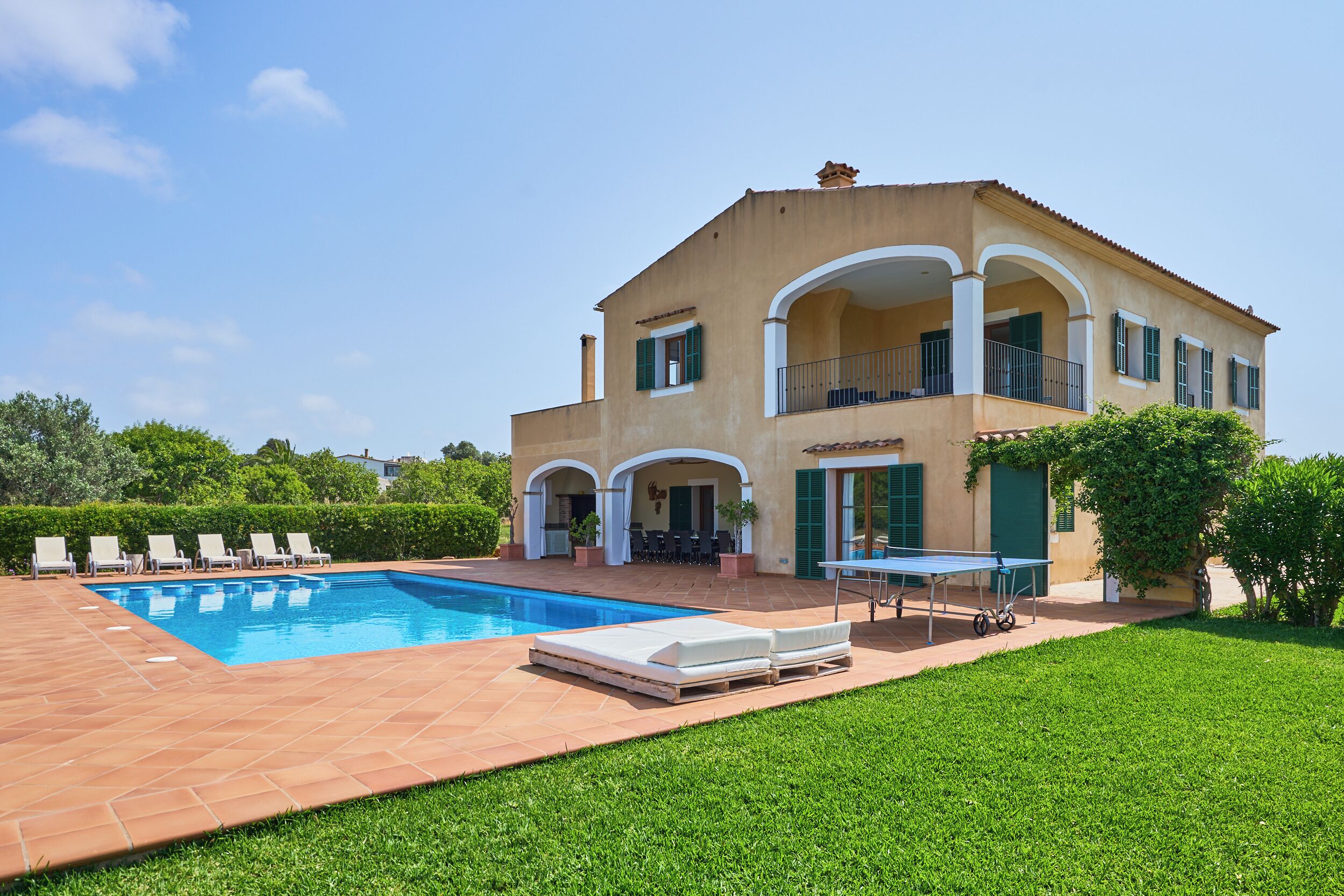 Ein zweistöckiges Haus mit Swimmingpool, Außenbereich zum Sitzen und einem Tischtennis-Tisch.