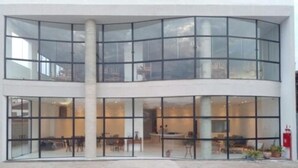 Um edifício moderno com fachada de vidro curvo, grandes janelas e uma coluna central.