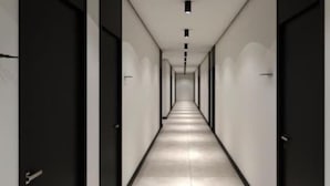 Um corredor comprido e estreito, com portas em ambos os lados, que leva a quartos.