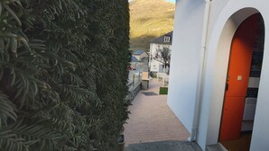 A narrow pathway leading to a building with a white exterior and an orange door. - Babylone apartment in a detached house (Luz-Saint-Sauveur)
