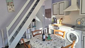 Une cuisine équipée d’une table à manger, de chaises, d’un lave-linge et d’un escalier.
