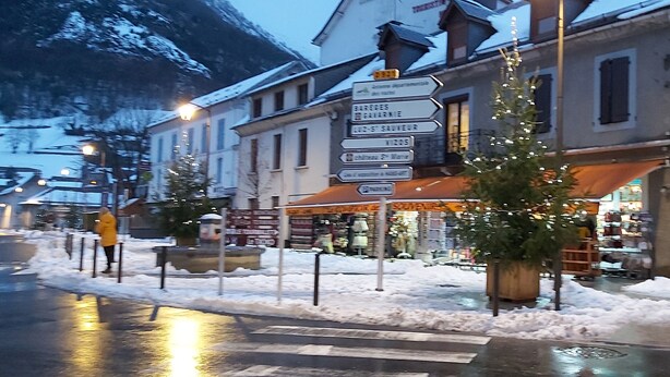 A street scene with a signpost, buildings, and a Christmas tree. - Babylone apartment in a detached house (Luz-Saint-Sauveur)