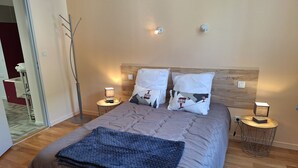 A neatly made bed with a quilted cover, two bedside lamps, and a bedside table with a lamp. - Babylone apartment in a detached house (Luz-Saint-Sauveur)