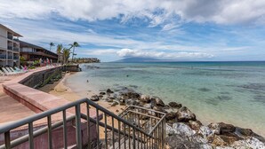 Un hotel frente a la playa con piscina, una escalera que lleva a la playa y vistas al océano.