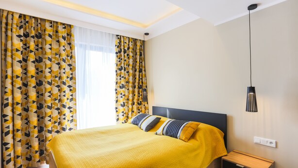 Une chambre à coucher moderne avec un lit, une table de chevet et une lampe suspendue.
